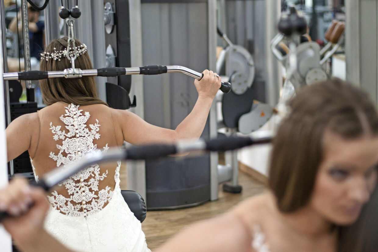 Young Woman Wearing A Bridal Dress And Exercising, Doing Shoulder And Upper Back Exercises At The Gym - Training For/Before Marriage, Preparing For Marriage Concept