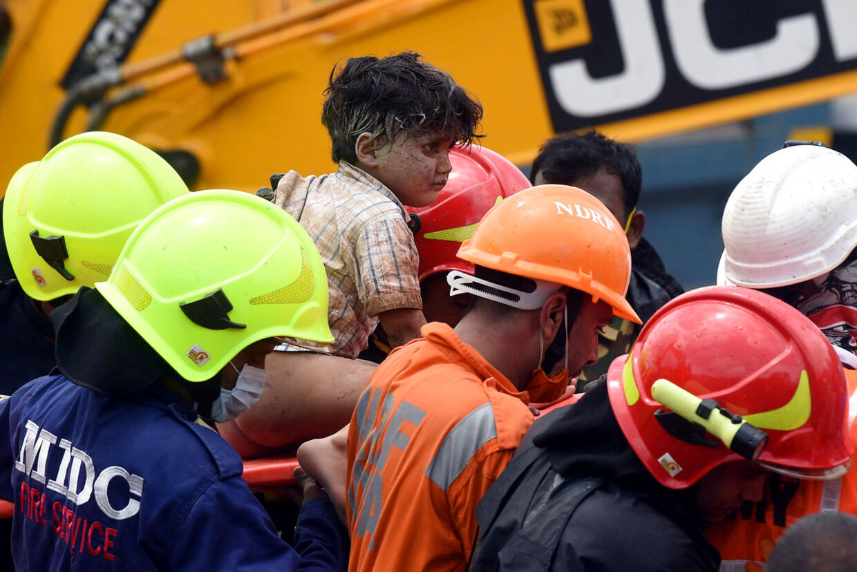 Redningsarbejdere bærer en fire-årig dreng ud fra murbrokkerne, efter han er blevet reddet ud af den kollapsede bygning