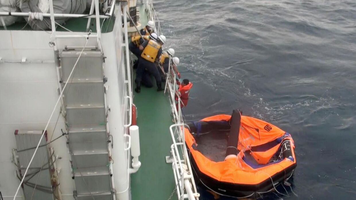 Redningsmedarbejdere står klar til at tage imod det 30-årige besætningsmedlem, der drev på en oppustelig redningsflåde. Japan Coast Guard/Reuters