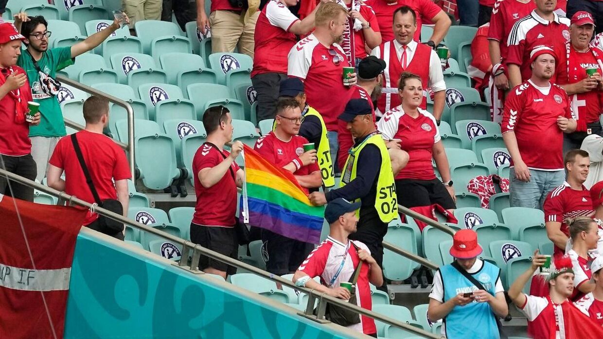 En steward på stadion tager fat i flaget, som de danske fans holder.