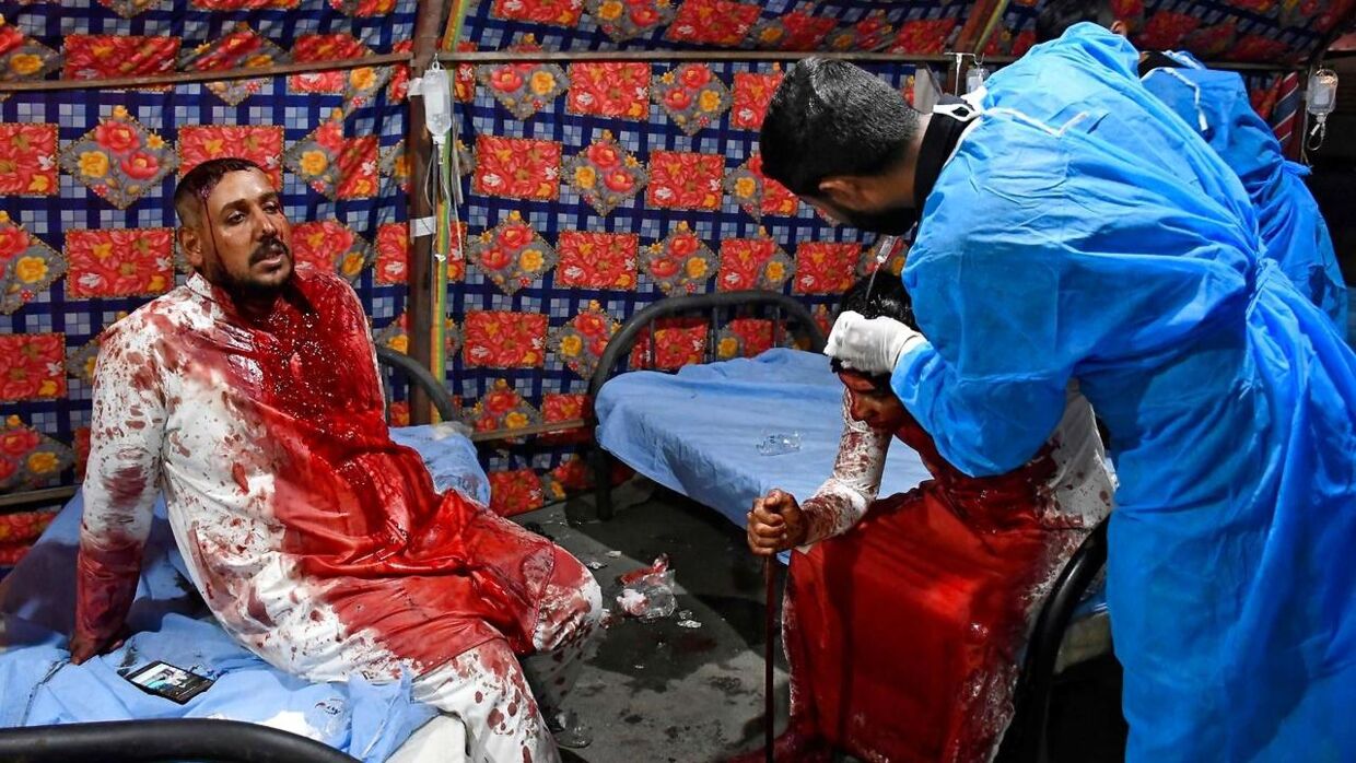 To irakiske mænd får lægehjælp efter at have skåret sig til blods i islamisk helligt optog.
