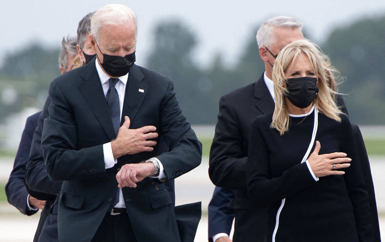 Både kameraer og tv-billeder fangede Joe Biden kigge på uret. Ved siden af ses hustruen Jill Biden.