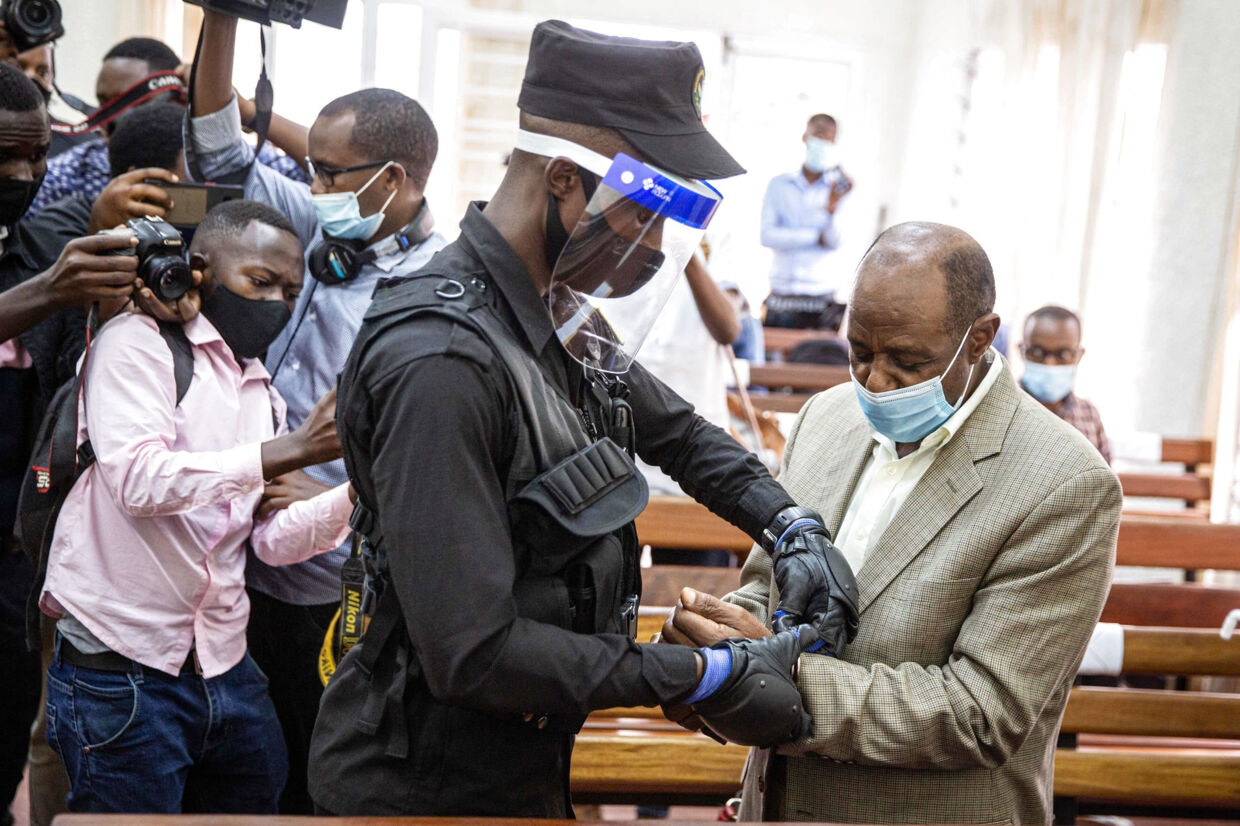 Paul Rusesabagina (til højre) får håndjern på efter et indledende retsmøde i forrige uge. Han er mandag blevet kendt skyldig i terroranklager ved en domstol i Rwandas hovedstad, Kigali. Stringer/Ritzau Scanpix