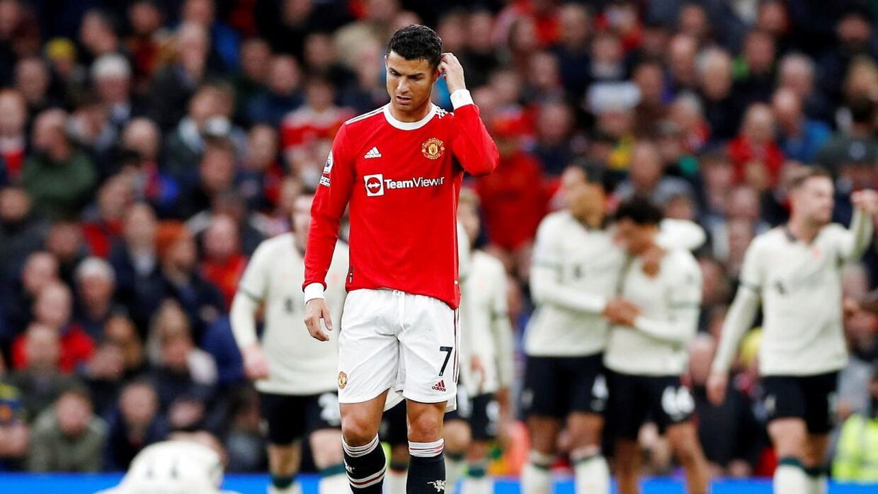 Cristiano Ronaldo går slukøret på græstæppet på Old Trafford, mens Liverpool-spillerne jubler i baggrunden.