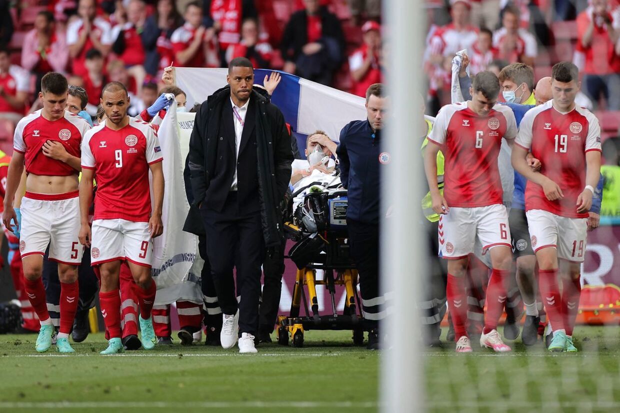 TOPSHOT - Denmark's players escort Denmark's midfielder Christian Eriksen (C) as he is evacuated after collapsing on the pitch during the UEFA EURO 2020 Group B football match between Denmark and Finland at the Parken Stadium in Copenhagen on June 12, 2021. (Photo by Friedemann Vogel / various sources / AFP)