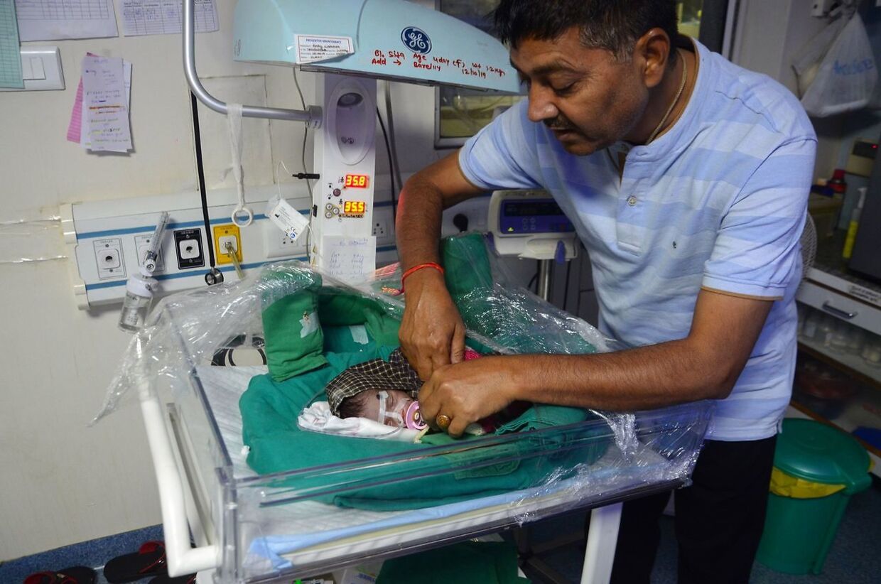 Den indiske politiker Rajesh Kumar Mishra kigger på en nyfødt babypige, som han er ved at adoptere i oktober 2019.