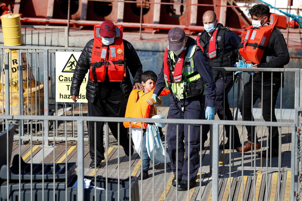 Et migrantbarn, der har klaret turen over kanalen, føres væk f de britiske myndigheder.