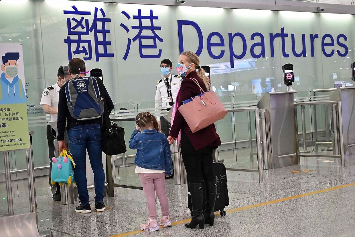 Familier til folk, der arbejder i Hongkong, står i kø for at forlade byen i den internationale lufthavn 8. marts 2022.