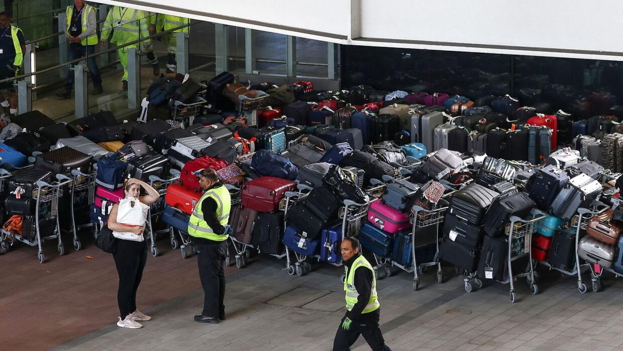 Airport workers stand next to lines of passenger luggage arranged outside Terminal 2 at Heathrow Airport in London, Britain, June 19, 2022. REUTERS/Henry Nicholls