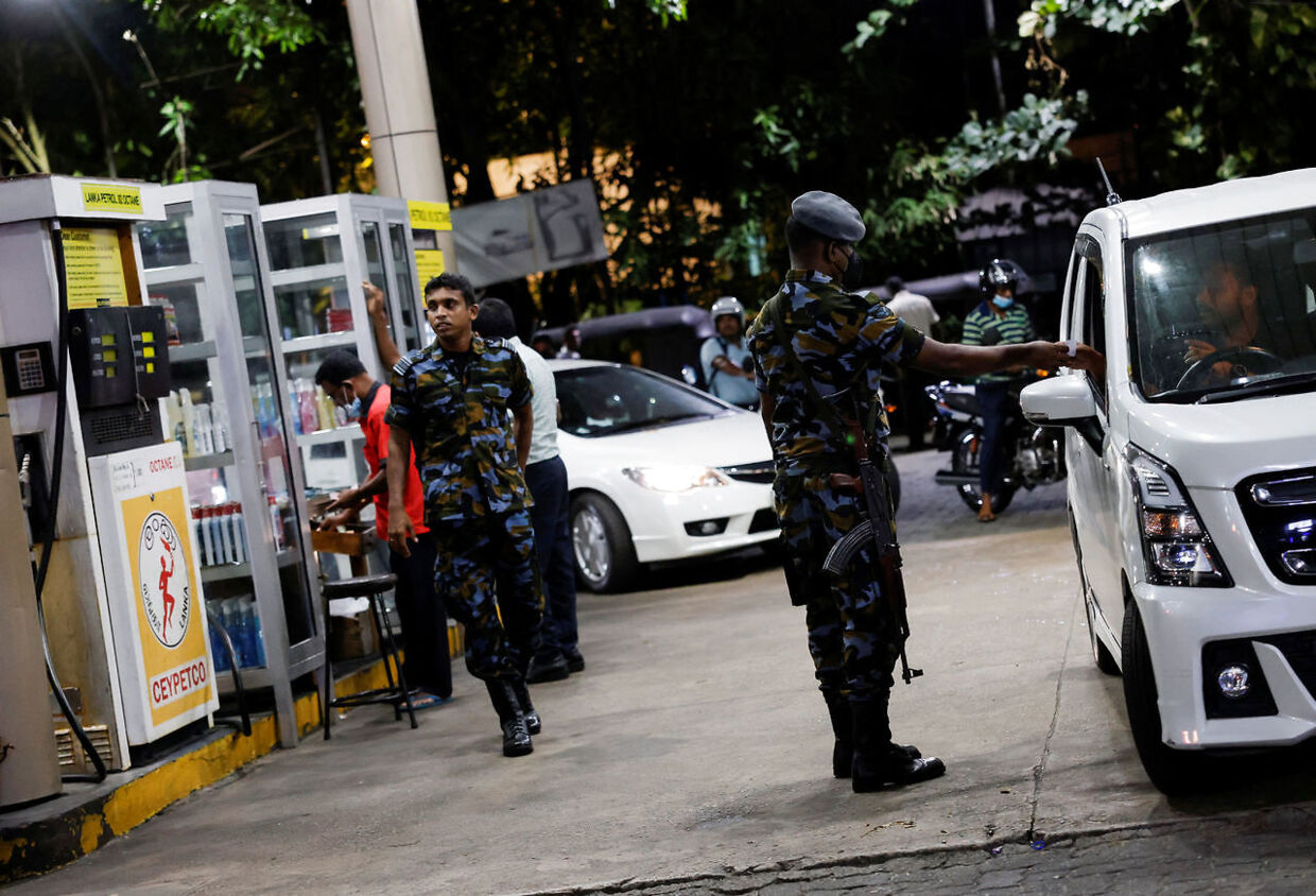 Et medlem af Sri Lankas luftvåben tjekker, om folk har lov til at holde i kø ved denne benzinstation.