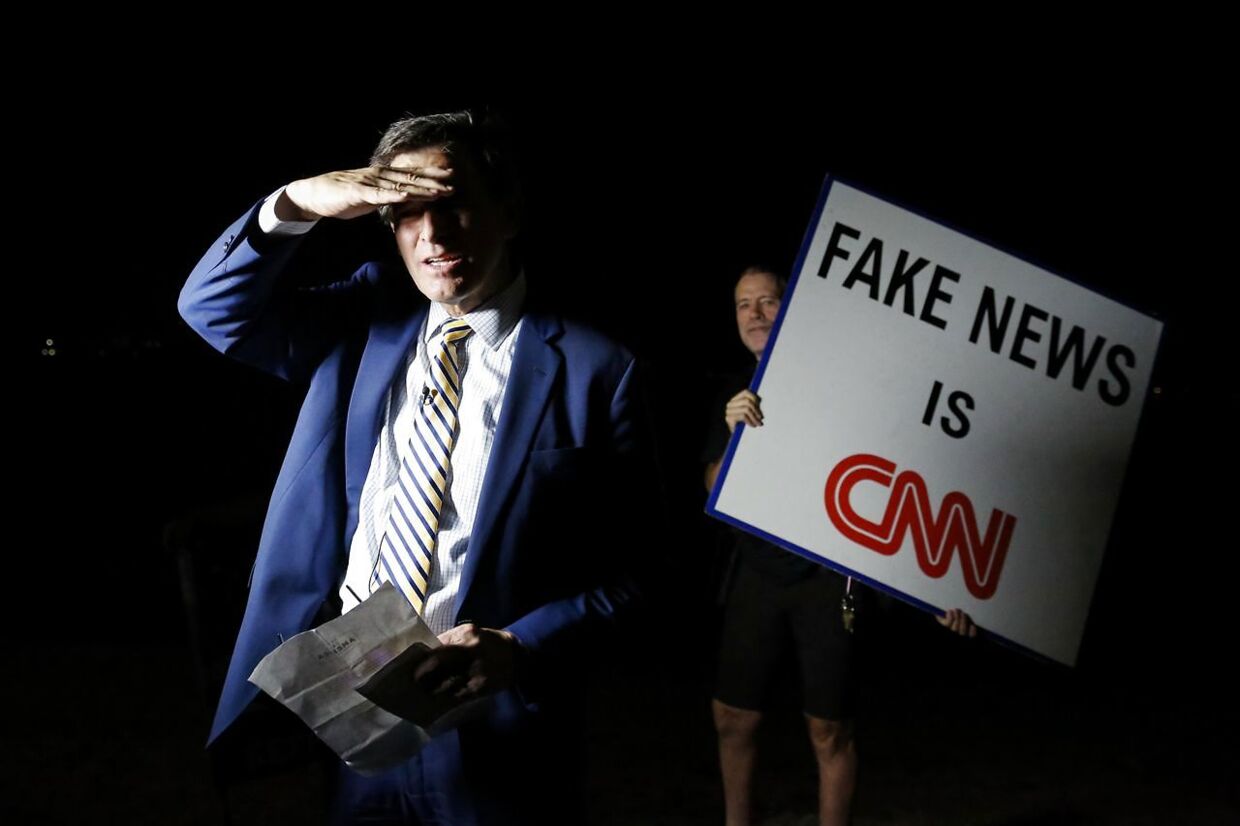 PALM BEACH, FL - AUGUST 08: A man holding a sign that reads Fake News is CNN stands next to Michael Williams, an anchor of Channel 5 WPTV (NBC affiliated) as he waits to go live outside of the home of former President Donald Trump at Mar-A-Lago on August 8, 2022 in Palm Beach, Florida. The FBI raided the home to retrieve classified White House documents. Eva Marie Uzcategui/Getty Images/AFP == FOR NEWSPAPERS, INTERNET, TELCOS & TELEVISION USE ONLY ==