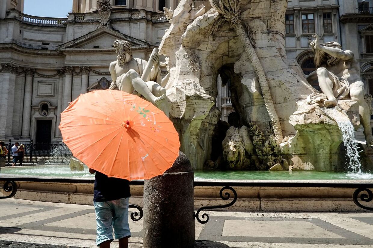 Turister i Rom bruger parasoller til at beskytte sig mod solens stråler.