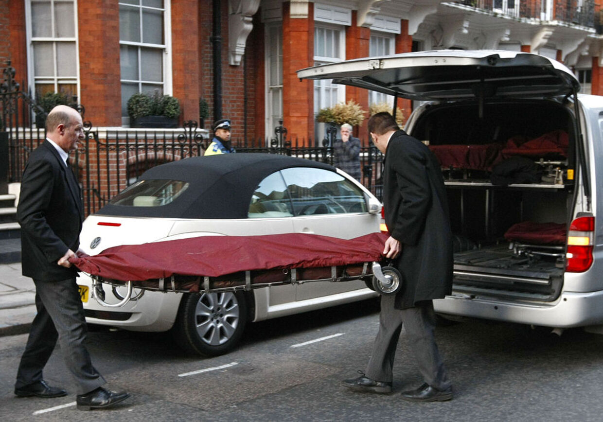 Her bliver McQueens lig båret ud af hjemmet og ind i en ambulance.