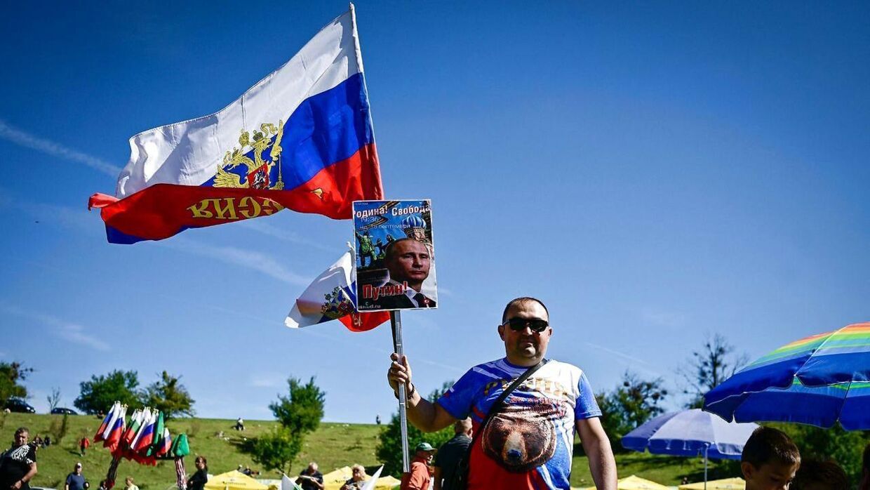 En mand poserer med et billede af Putin og det russiske flag til fejringen i byen Kalofer.