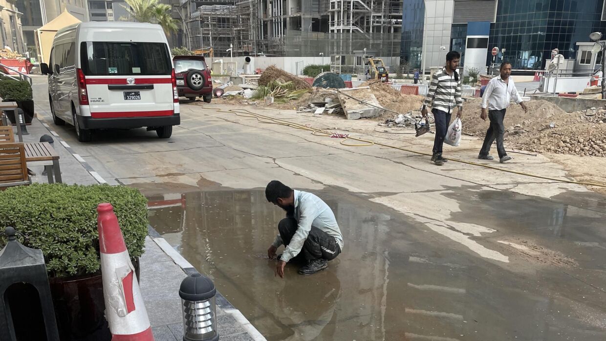 En migrantarbejder i det centrale Doha forsøger at køle sig ned ved at plaske vand på sine fødder fra en mudderpøl. Temperaturen var over 35 grader i skyggen på tidspunktet.