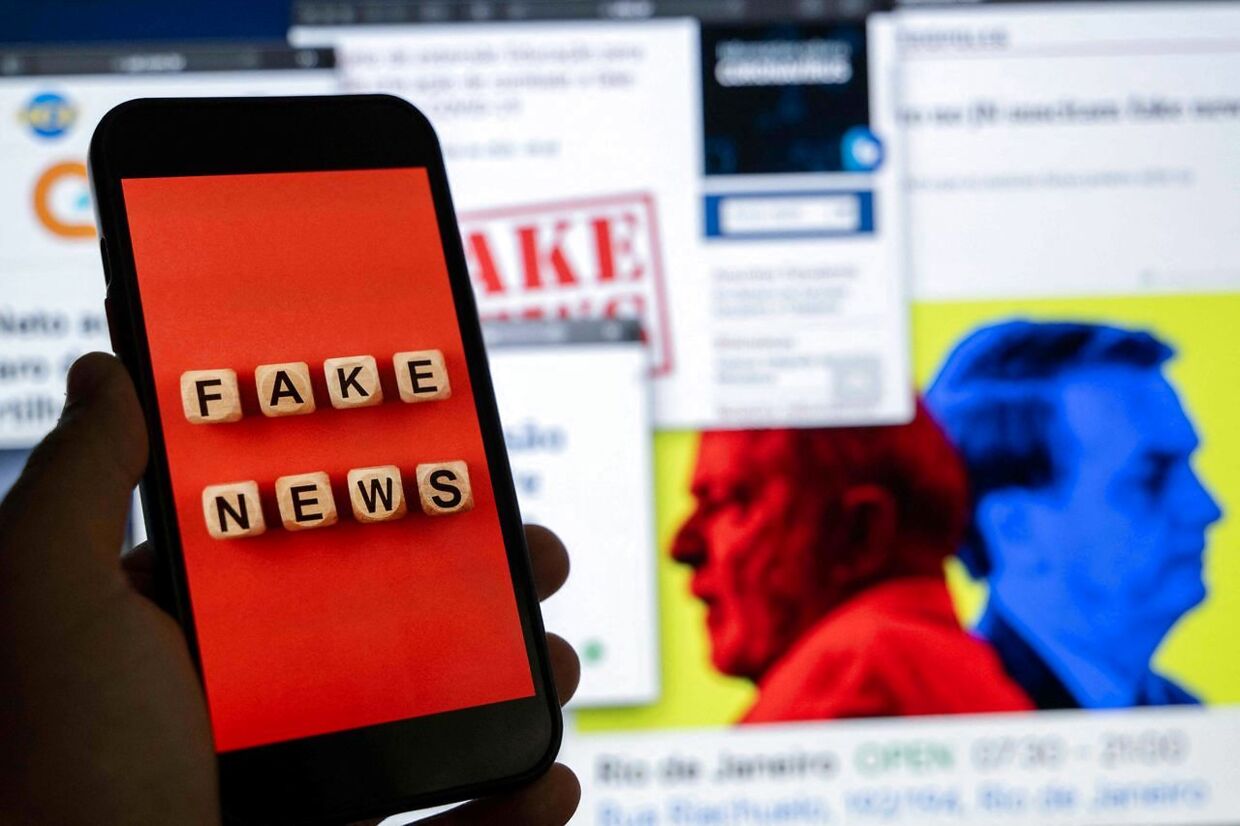 Billedet viser en mobiltelefon med ordene 'fake news' foran en tv-skærm fuld af nyheder og rapporter om falske nyheder i Brasilien.