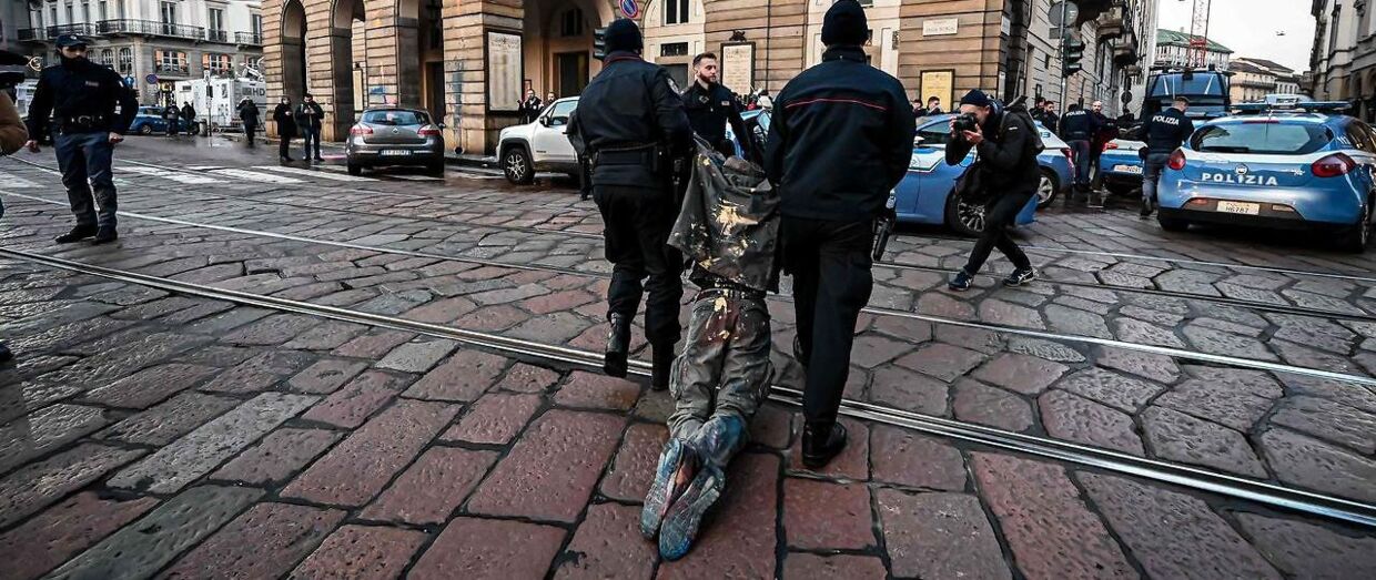 Politiet slæber væk med klimaaktivist efter male-protest i Milano. Foto Piero Cruciatti / AFP.