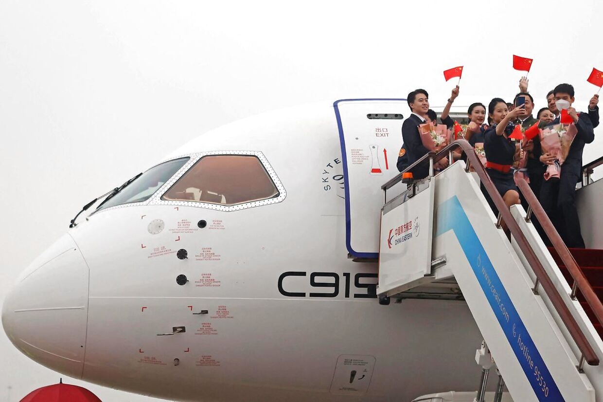 Medlemmer af besætningen vifter med de kinesiske flag efter at være landet med C919-flyet i Hongqiao International Airport i Shanghai.