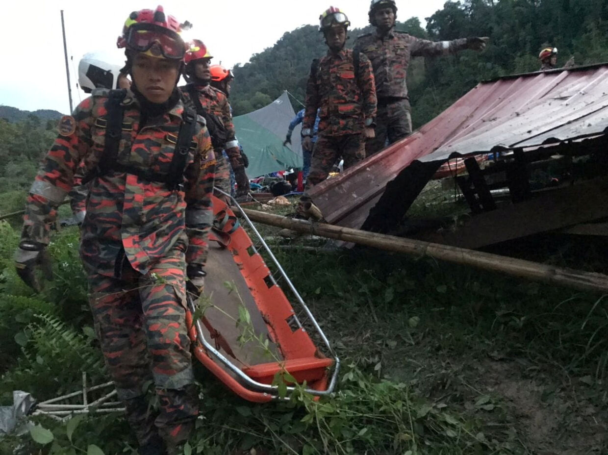 Redningsfolk bærer bårer på vej ind til jordskreddet godt 50 kilometer nord for Kuala Lumpur.