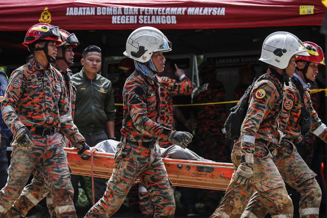 Redningsfolk fra det malaysiske brand- og redningsvæsen bærer et offer for jordskreddet bort.