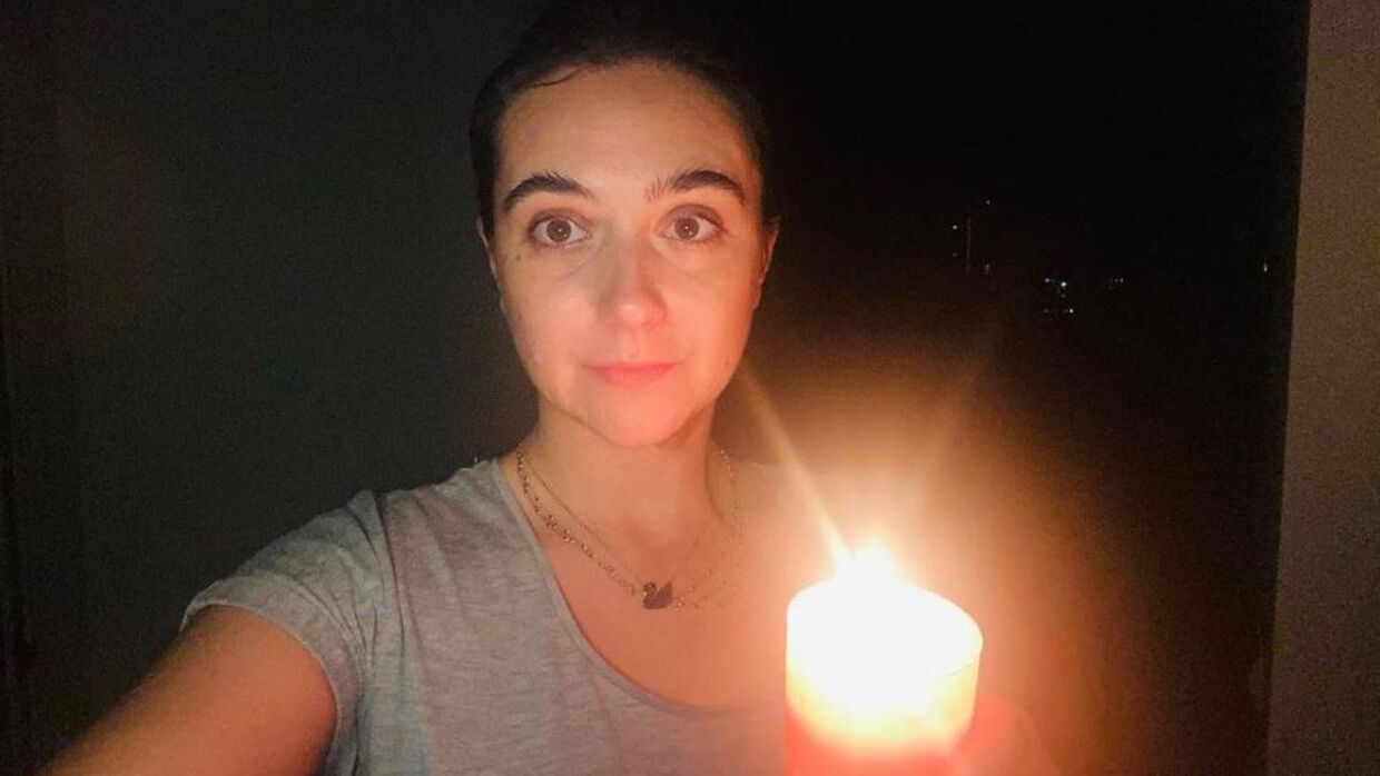 Iuliia Mendel i skæret fra et stearinlys, som hun må bruge, når russiske bomber får strømmen i Kyiv til at forsvinde.