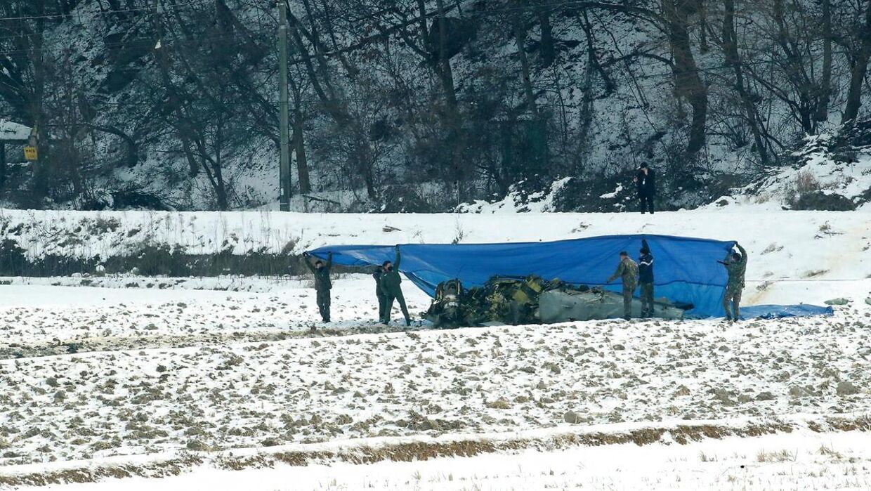 Sydkoreansk militærpoliti tildækker et stedstyrtet kampfly, som blev sendt i luften for at nedskyde en fjendtlig drone. 26 December 2022. EPA/YONHAP SOUTH KOREA OUT