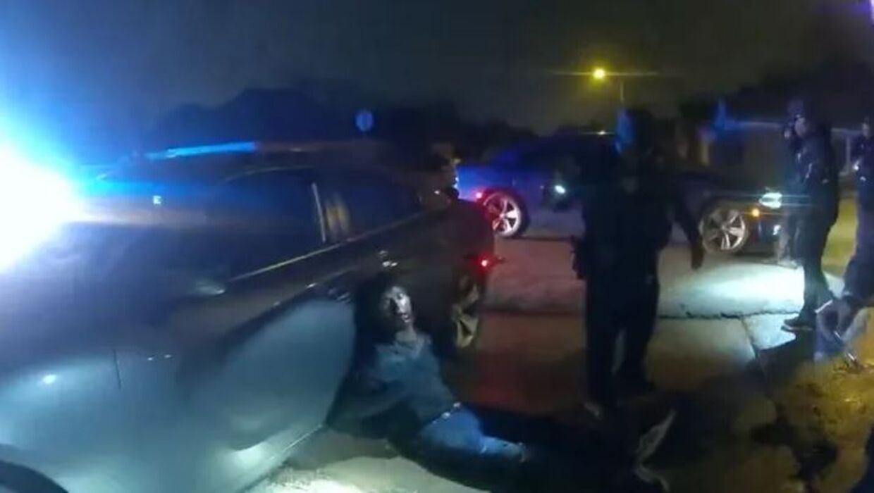 Tyre Nichols ses siddende med ryggen op mod en politibil.