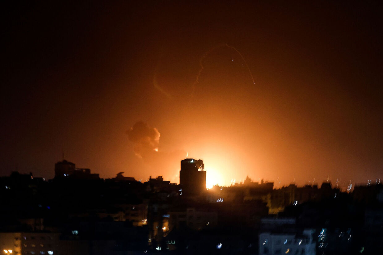 Ild og røg stiger op blandt bygninger i Gaza efter luftangreb fra det israelske militær. Mohammed Abed/Ritzau Scanpix