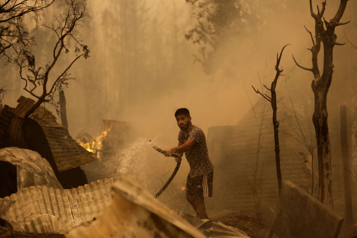 En beboer i Santa Juana nær Concepcion i Chile forsøger fredag at slukke flammerne fra en skovbrand. Juan Gonzalez/Reuters
