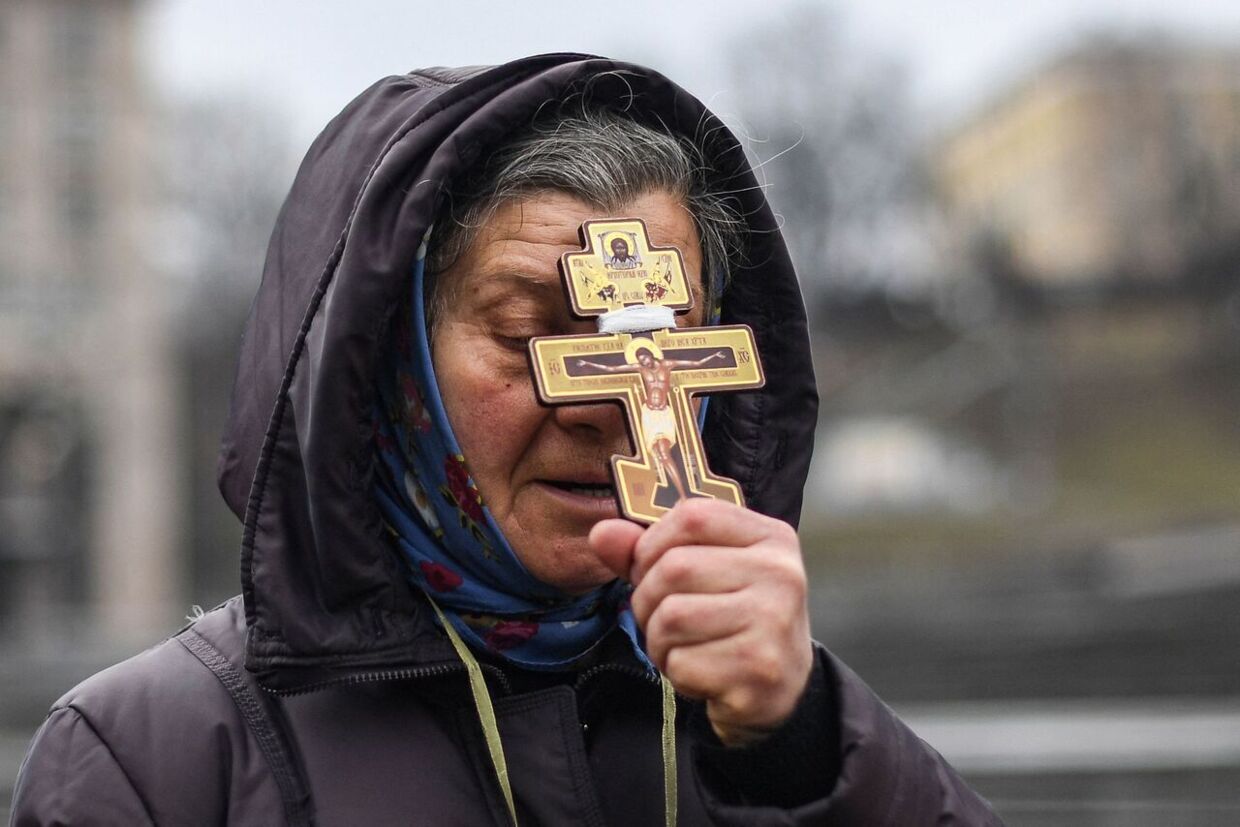 En ukrainsk kvinde holder et kors op for ansigtet 24. februar 2022. Stemningen i Kyiv var, at russerne ville overløbe hovedstaden i løbet af kort tid.