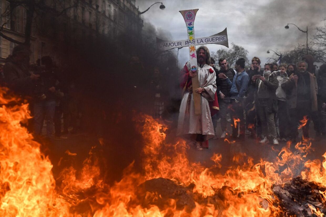 En demonstrant i Paris er klædt ud som Jesus og holder et skilt med teksten 'kærlighed ikke krig', der var dog mere krig end kærlighed på Place de la Nation tirsdag aften