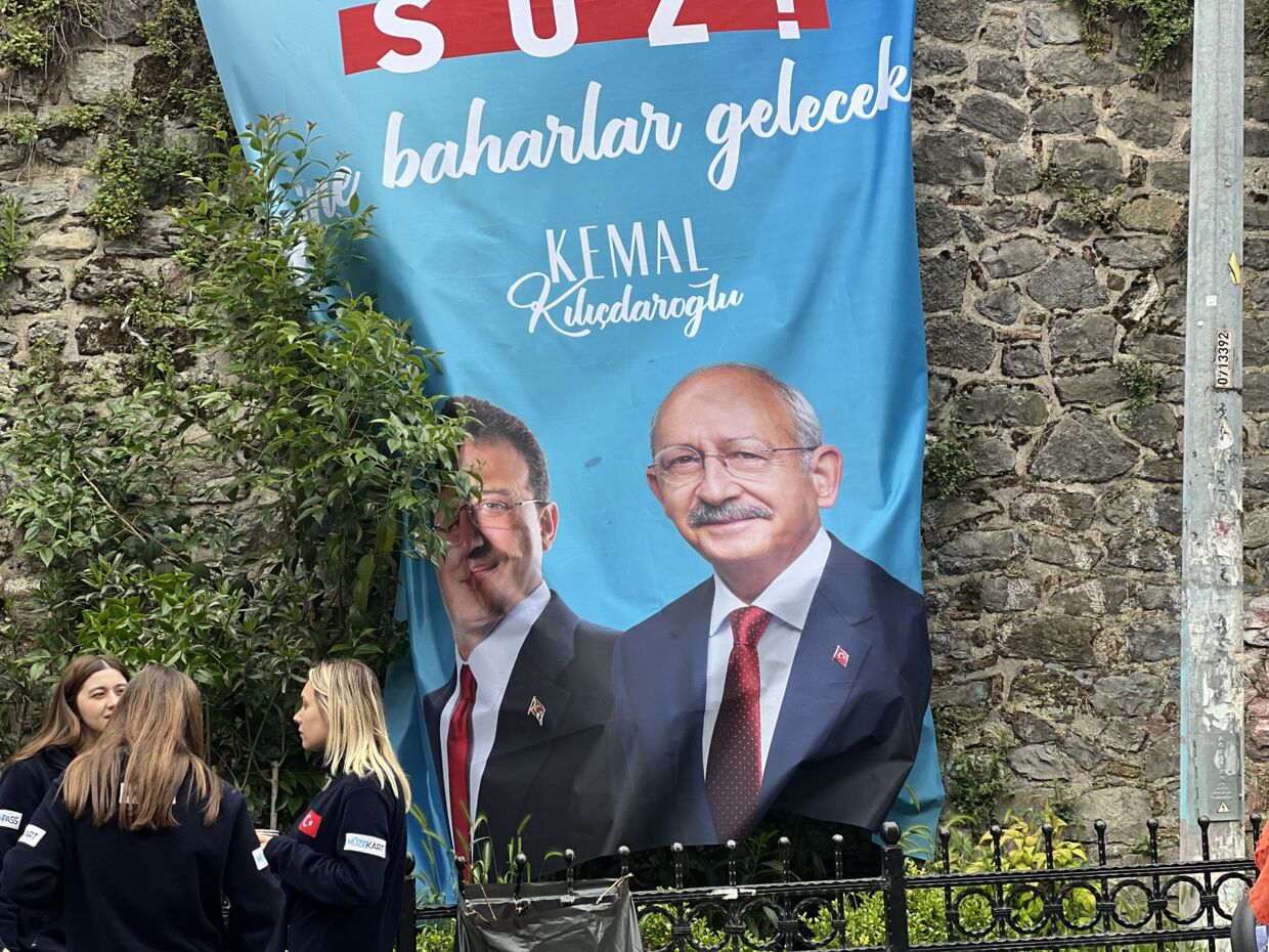 En gruppe unge står og snakker under en plakat for oppostionsleder Kemal Kılıçdaroğlu i Istanbul.