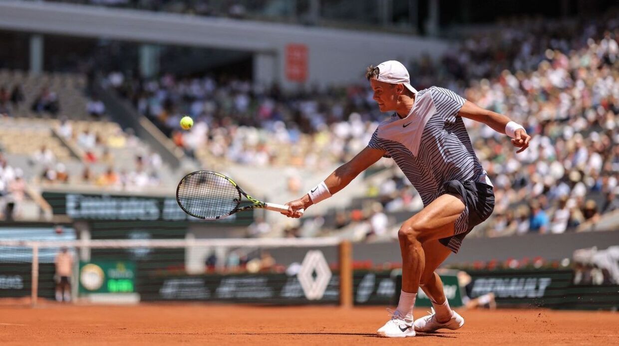 Denmark's Holger Rune plays a backhand return to Argentina's Genaro Alberto Olivieri during their men's singles match on day seven of the Roland-Garros Open tennis tournament at the Court Philippe-Chatrier in Paris on June 3, 2023. (Photo by Thomas SAMSON / AFP)