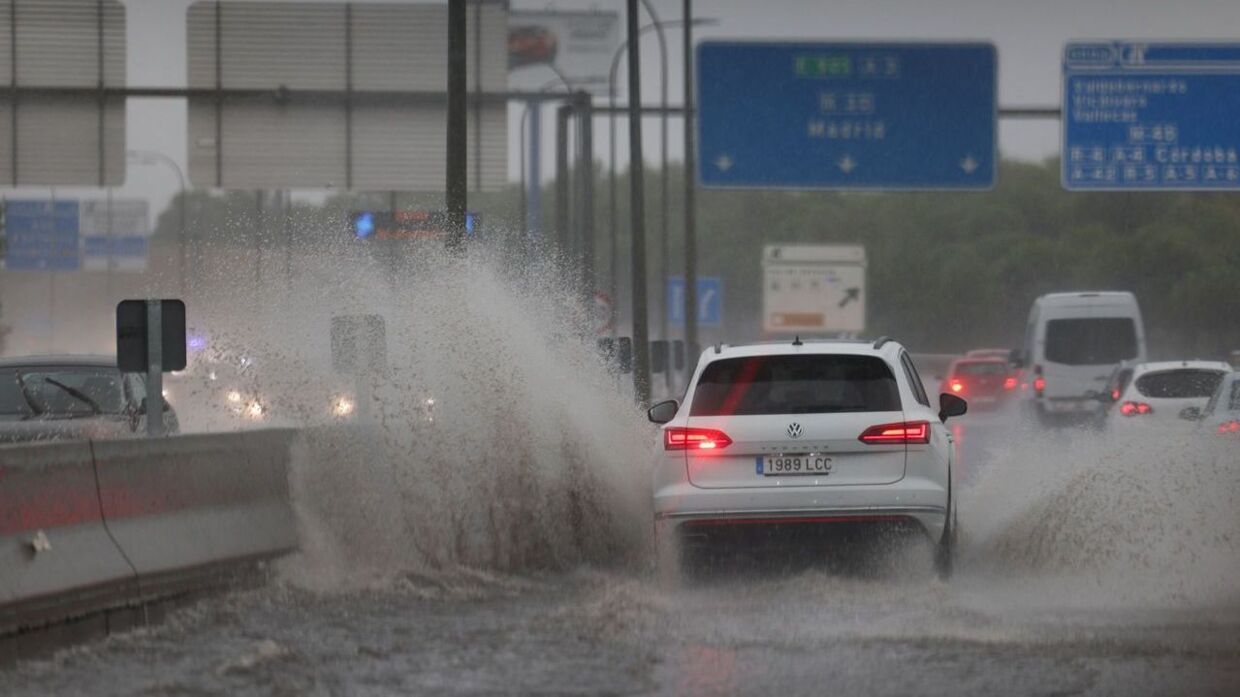 En bil kører igennem en kæmpe vandpyt ved Spaniens hovedstad Madrid.