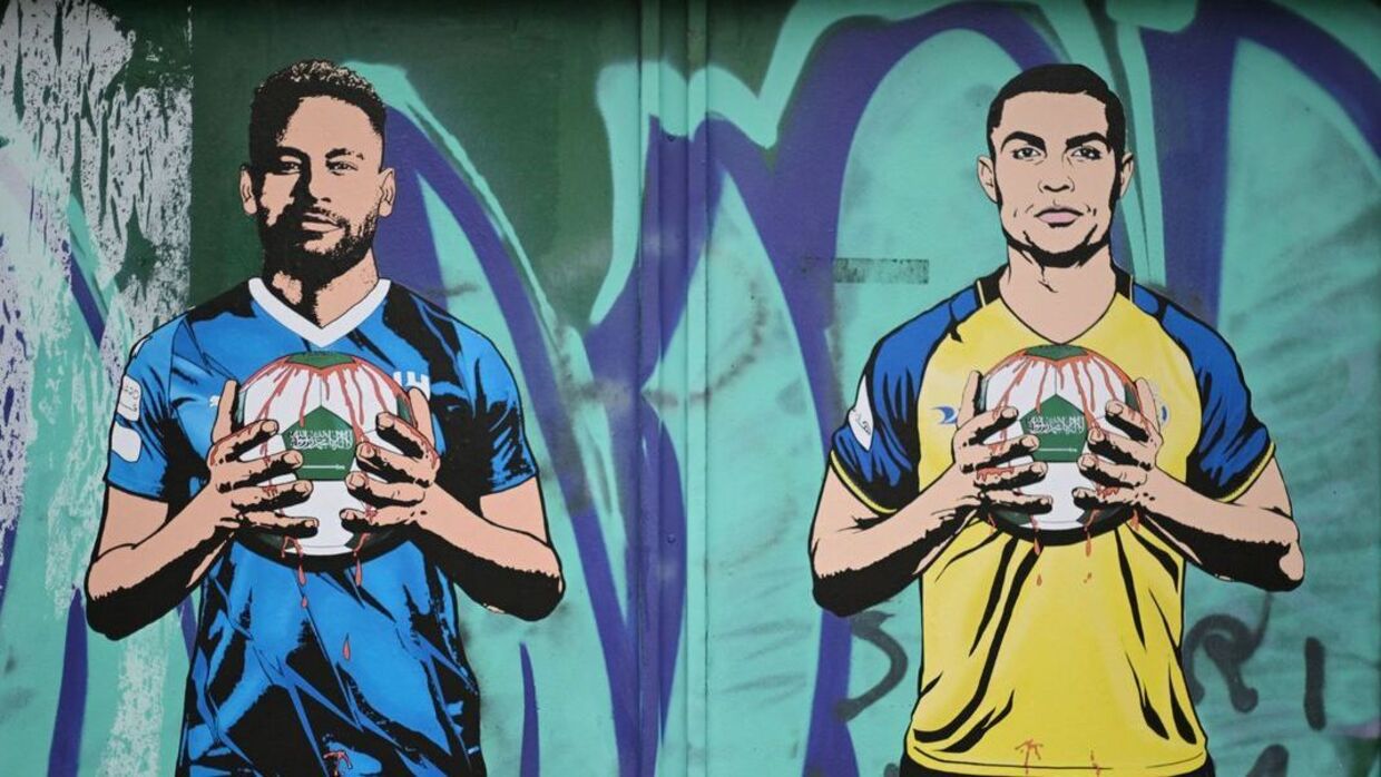 Neymar og Cristiano Ronaldo holder fodboldbolde med Saudi-Arabiens flag, der er smurt ind i blod. De er bare to af mange stjerner, der er skiftet til landets fodboldklubber. Vægmaleriet er dukket op i Milano.