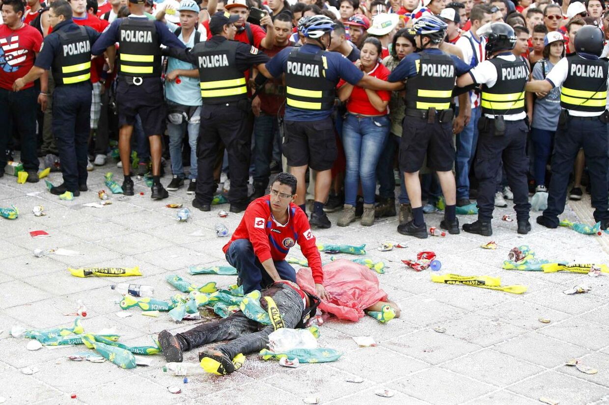 Fodboldfest i Costa Rica blev omdannet til voldeligt optøjer. Her behandler en paramediciner en såret efter optøjerne.