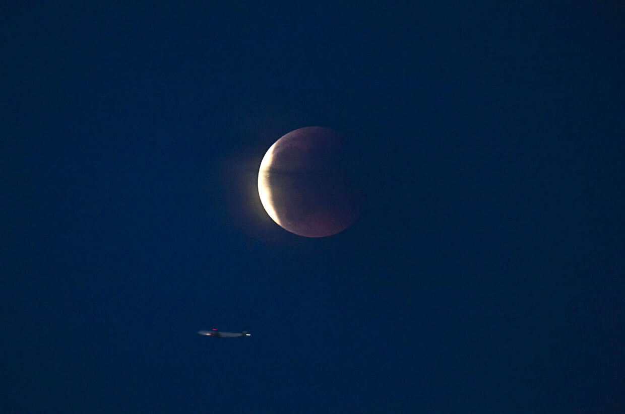 bt.dks fotograf måtte vente i næsten to timer i Dragør, før den formørkede måne tittede frem. Her ses den med et fly i forgrunden.