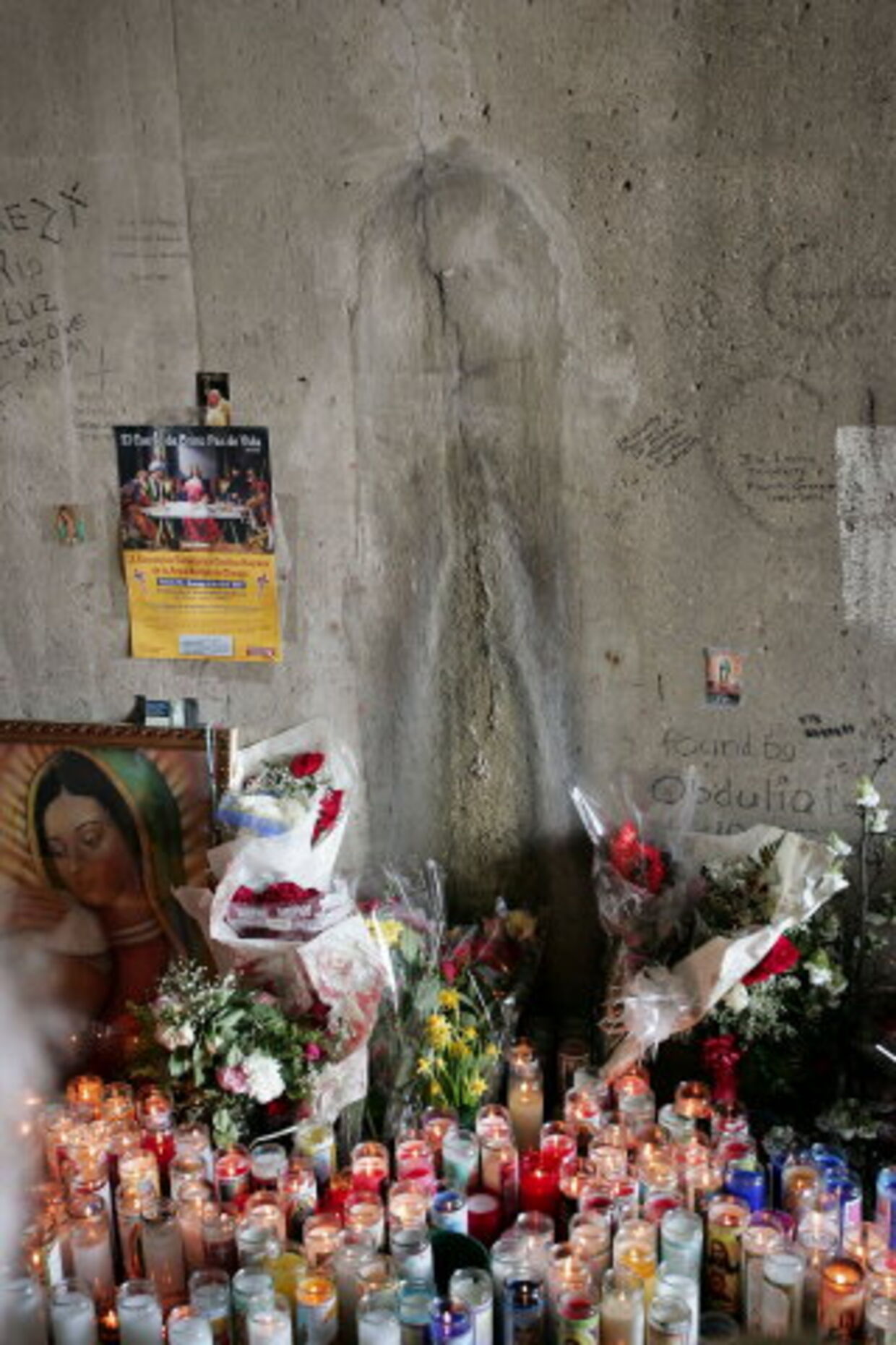 Troende har tændt levende lys og lagt blomster foran aftegningen, som de mener forestiller Jomfru Maria. Foto: Getty/All Over Press
