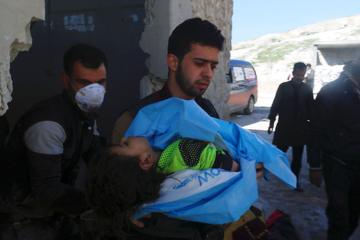 En mand bærer et dødt barn væk, efter angrebet på Khan Sheikhoun.